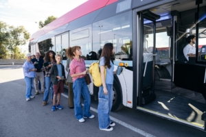people waiting to board a bus on street